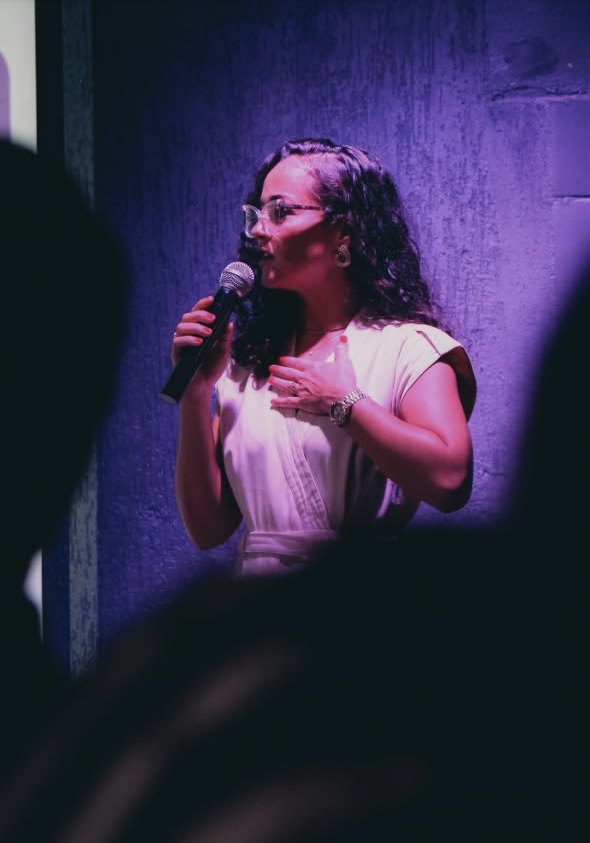 Luana Trindade falando ao microfone para a plateia