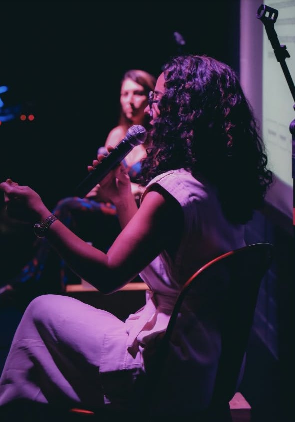 Luana Trindade de perfil, falando ao microfone