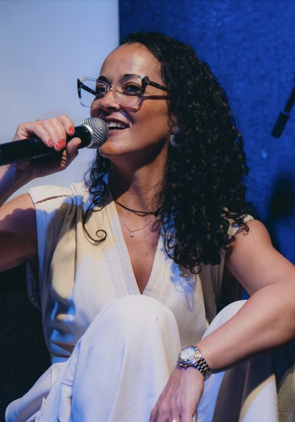 Luana Trindade sorrindo ao microfone durante a palestra